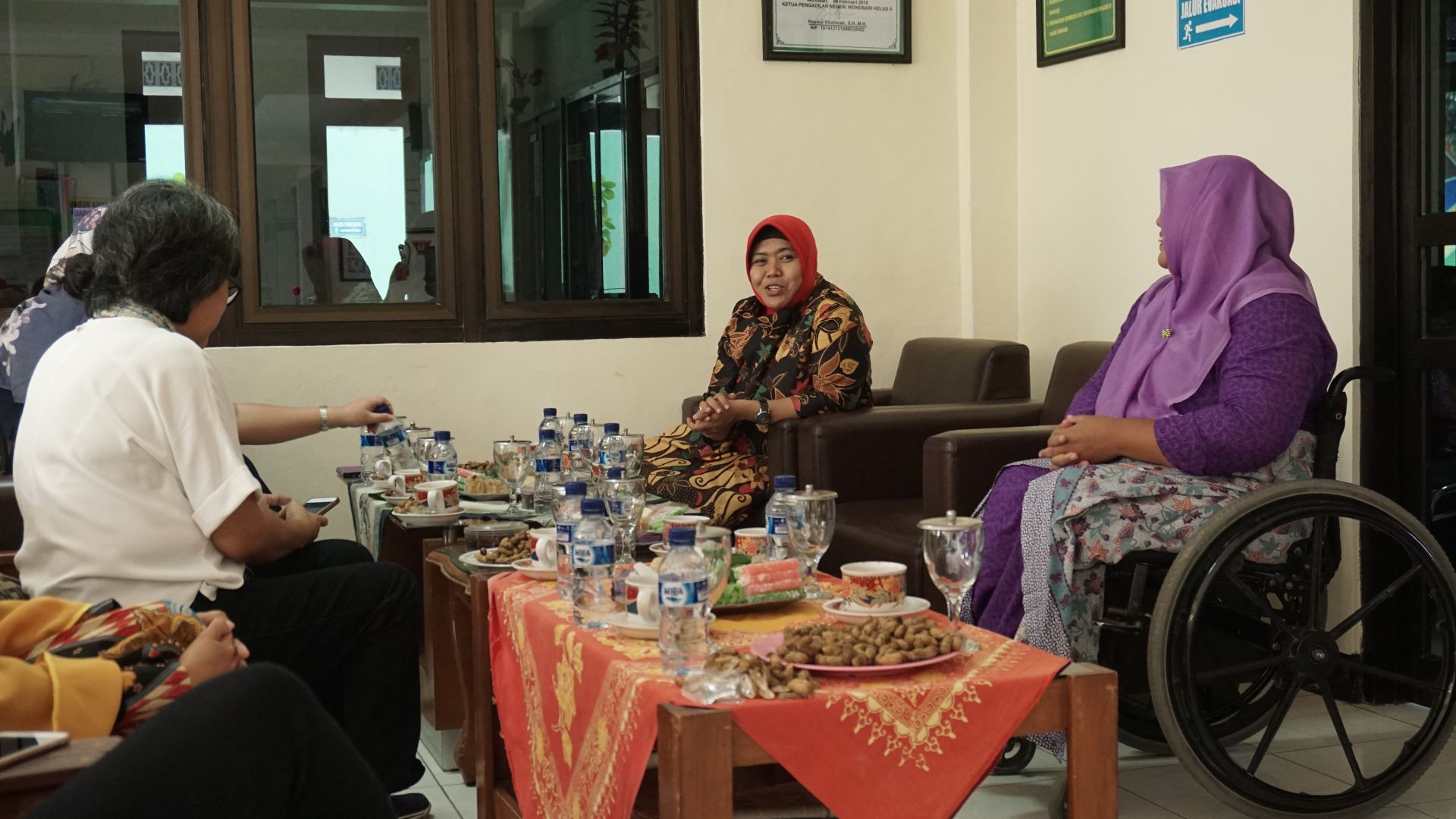 Khotimah, Ipung and other court staff discuss inclusive court ideas while snacking.