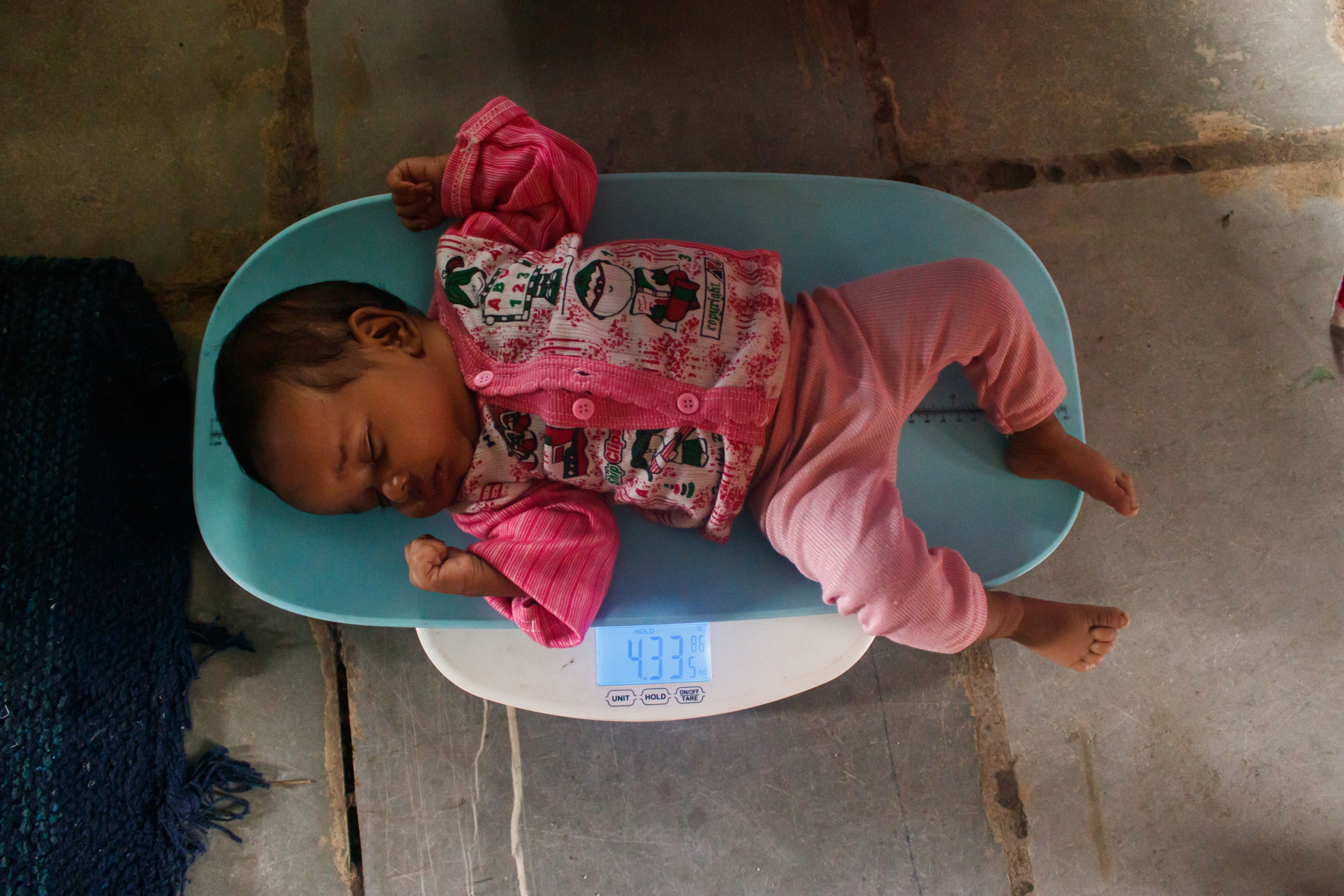 Healthcare workers monitoring the weight of an infant during a health checkup camp.