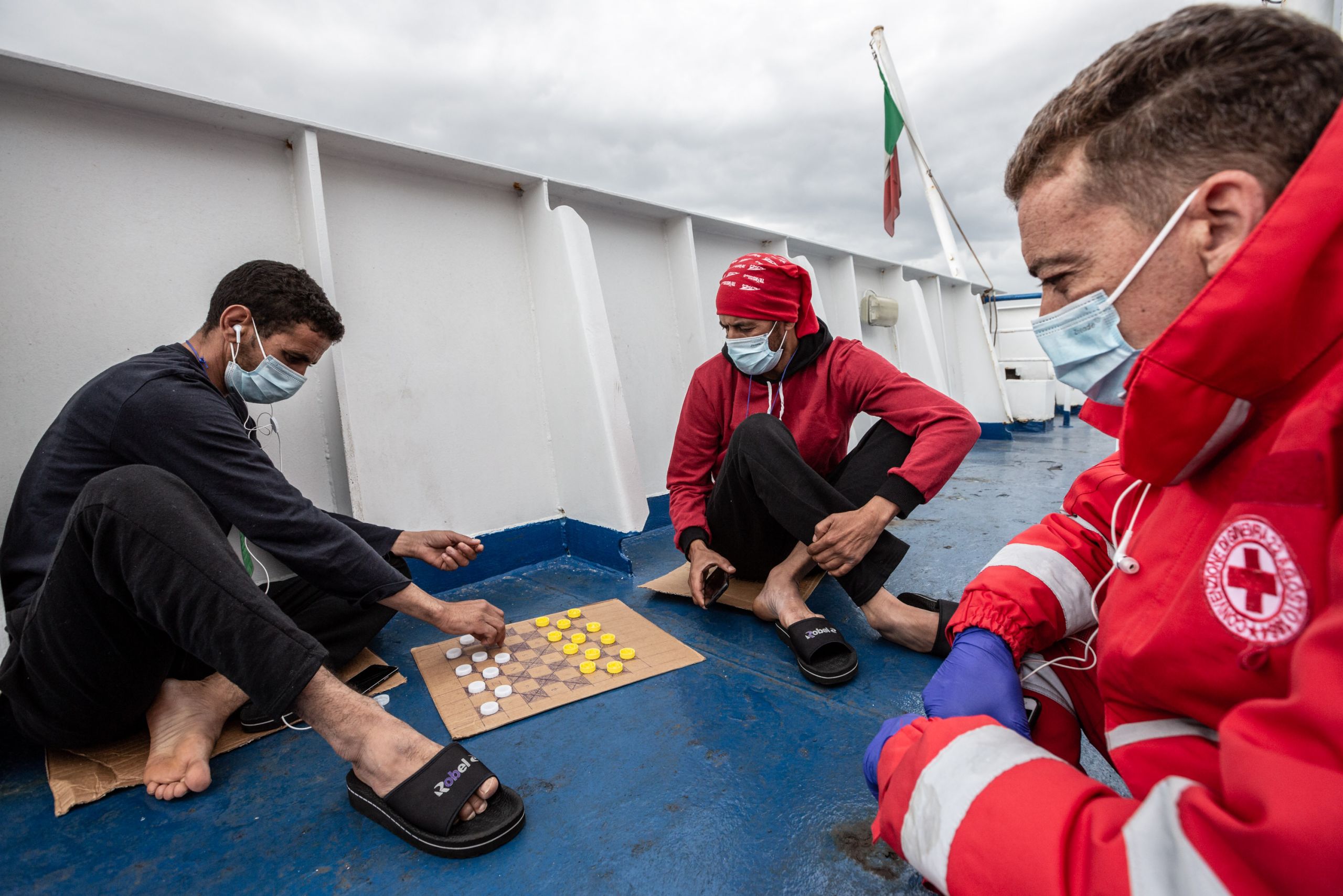 Migrants play a game of chequers abroad the boat
